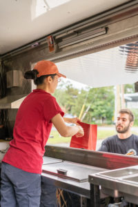 Sola serving a customer at her food truck in Wareham