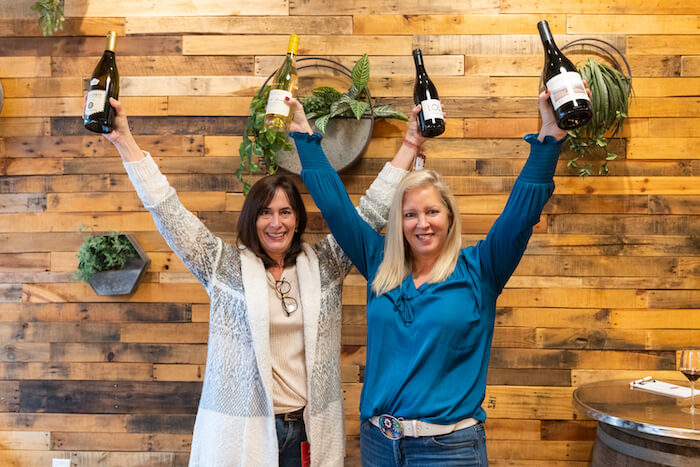 Michelle and Katy holding up bottles at Uva in Plymouth
