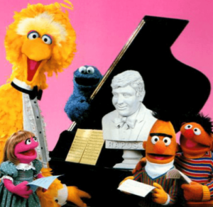 Sesame Street characters gathered around a piano and bust of Joe Raposo