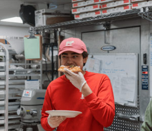 One of the cooks, eating a slice of pizza