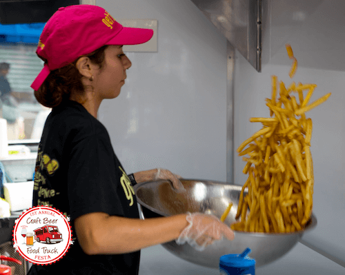 Chef holding a bowl of french fries being tossed in the air with salt
