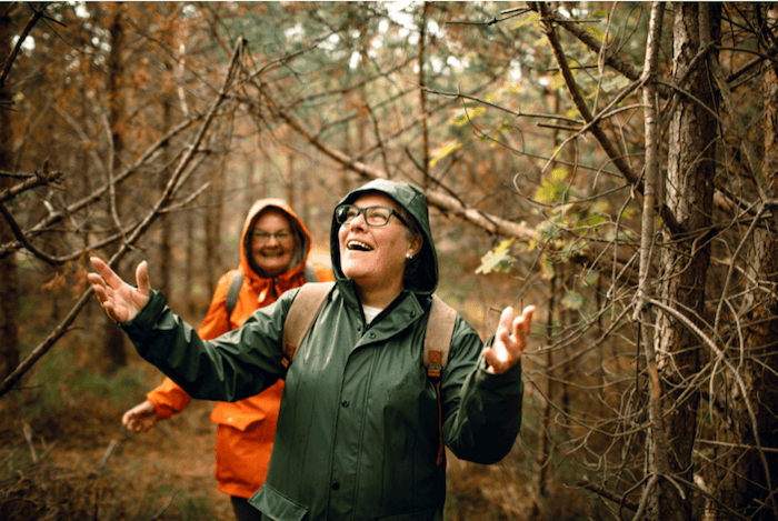 2 women hiking in the woods in rain gear