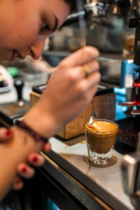 A barista carefully finishes an espresso drink