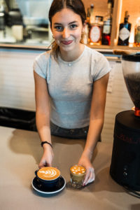 A barista presenting two drinks