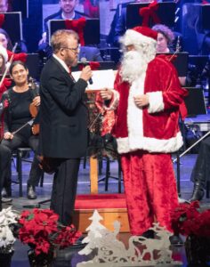 Santa talking with a man in a tuxedo in front of the Symphony