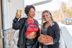 Staffers outside the River Junction holding the featured pizza and beer
