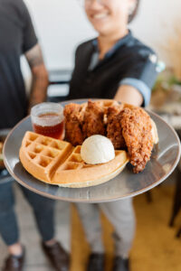 Faye holds out the chicken and waffles dish