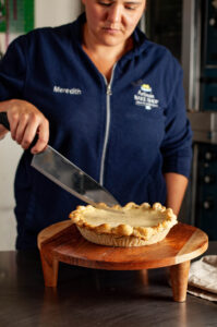 Meredith Rousseau cuts a pie.