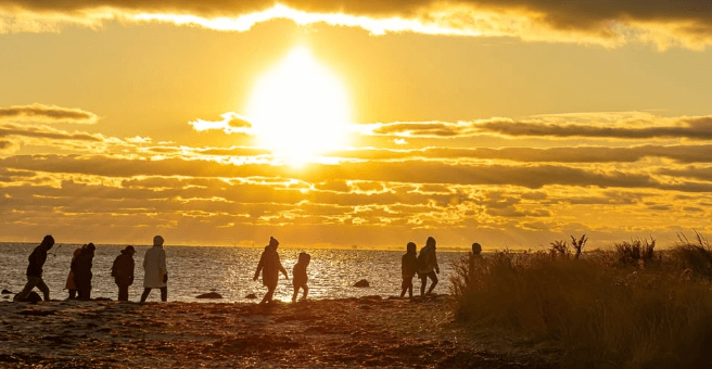 People walking along the shore at sunset