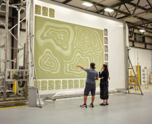 Tufting Operator Vicheth Kragn and Tiffany Megumi Gerdes inspect a rug at the tufting machine