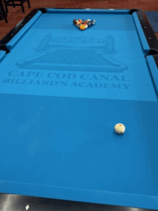 A billiard table with Cape Cod Billiards Academy spelled out in shadow