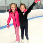 2 girls ice skating at the rink