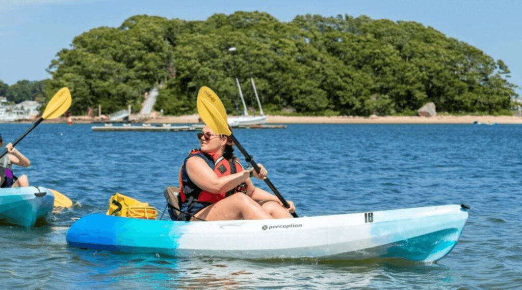 A woman kayaking with Wickets Island in the background