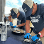 Two people shucking oysters