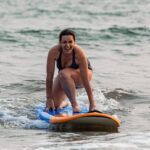 A woman about to stand up on a surfboard