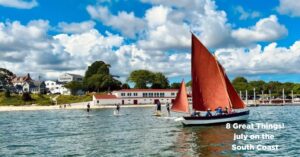 Sailboat with red sail in front of the Onset Bay Center
