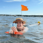 A woman in the water holding up 5 poker playing cards