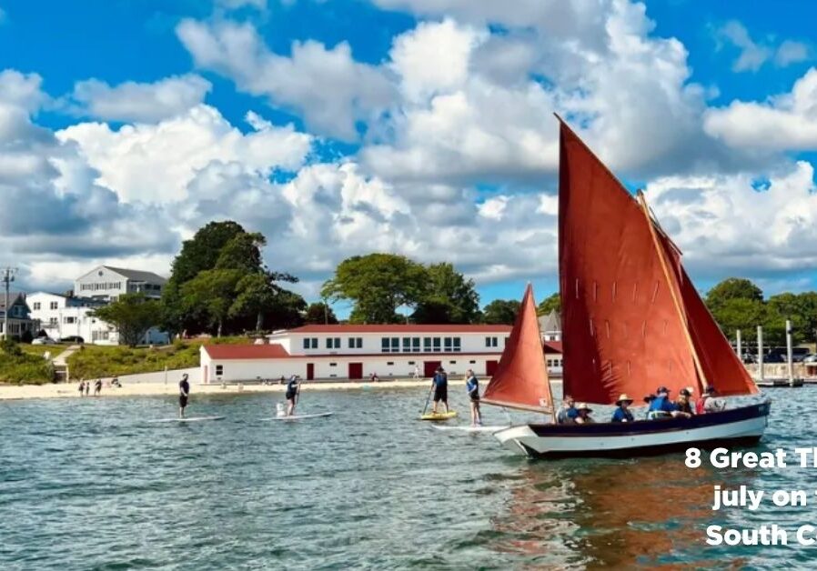 Sailboat with red sail in front of the Onset Bay Center