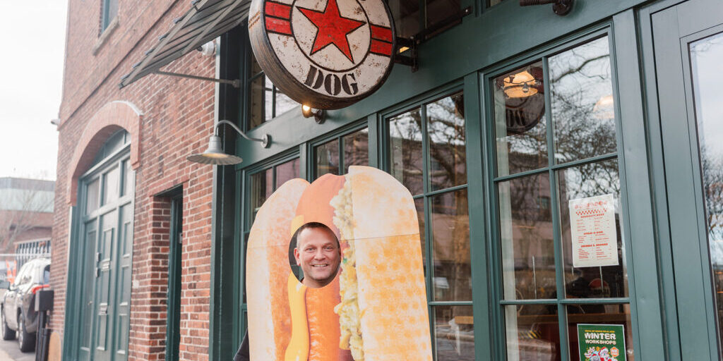 Adam standing outside Bomb Dog, in a hot dog costume