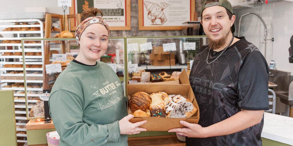 Allie and Mike at their bakery holding a box of treats