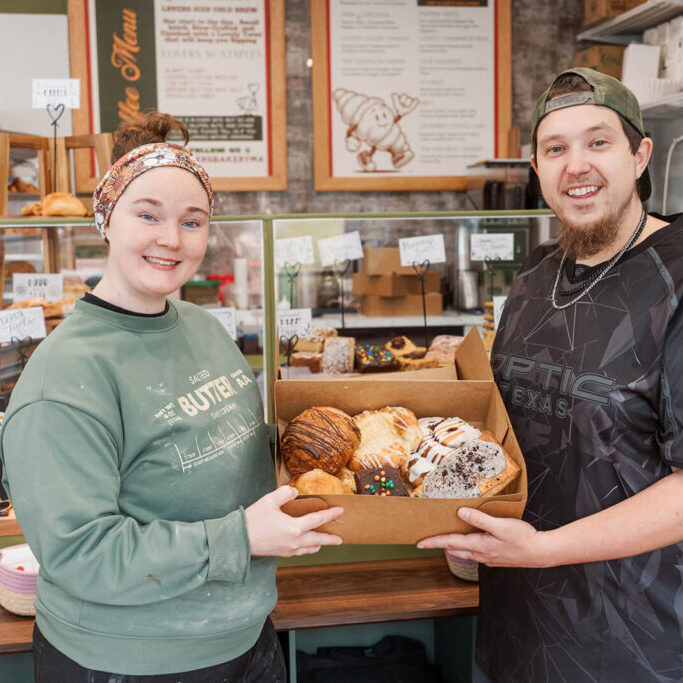 Allie and Mike at their bakery holding a box of treats