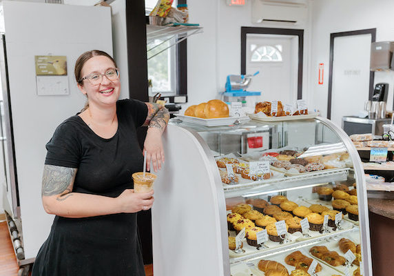 Joni Rhodes leaning against her pastry case at The Rescue Cafe