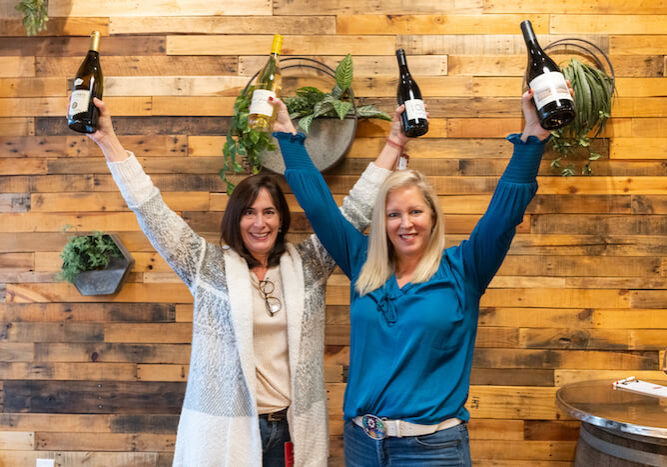 Michelle and Katy holding up bottles at Uva in Plymouth