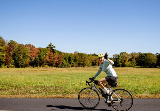 A watershed rider bicycling with a field in the background