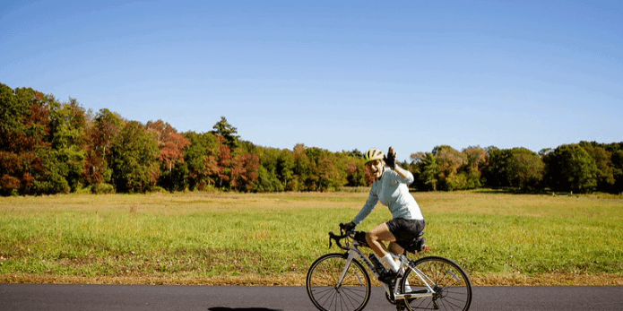 A watershed rider bicycling with a field in the background