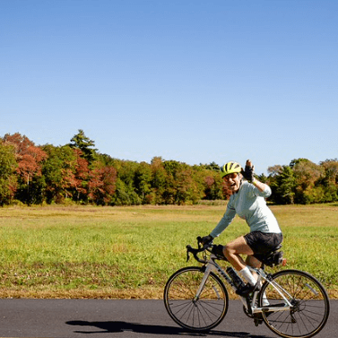 A watershed rider bicycling with a field in the background