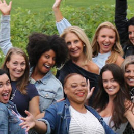 A group of women outside, smiling and holding their hands in the air